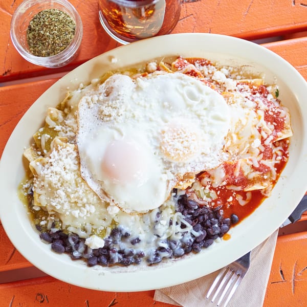 El Sancho Loco's chilaquiles with red and green sauce, black beans, cheese, and two fried eggs.