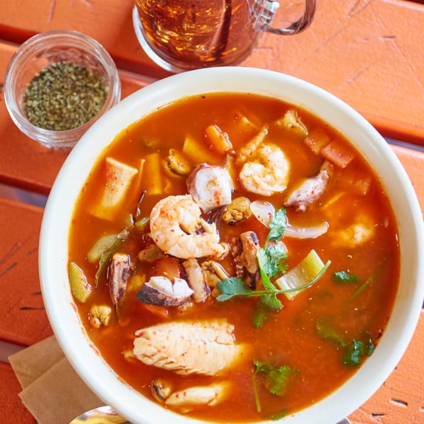 El Sancho Loco's vibrant seafood soup with shrimp, octopus, and mussels, garnished with cilantro.
