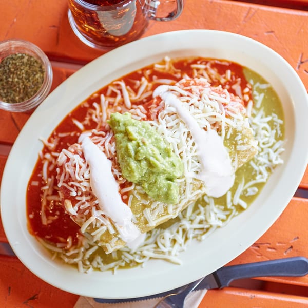 El Sancho Loco's enchiladas with red and green sauce, cheese, guacamole, and sour cream.