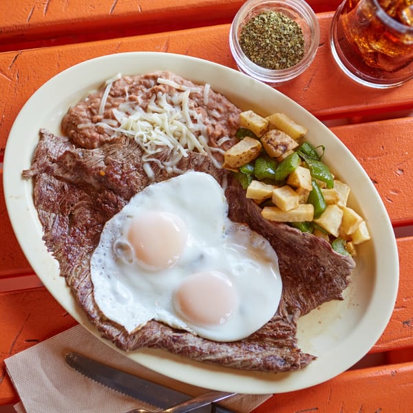 El Sancho Loco's Mexican breakfast with steak, two fried eggs, refried beans, and potatoes.
