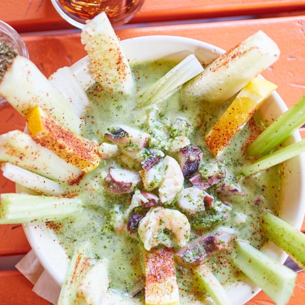 El Sancho Loco's vibrant green Mexican seafood cocktail with shrimp, octopus, celery, and chili powder.